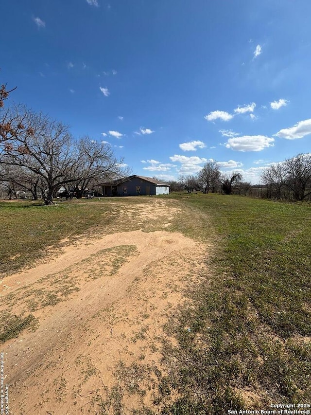 view of yard featuring a rural view, a pole building, and an outbuilding