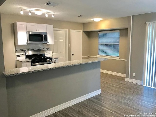 kitchen with visible vents, white cabinets, dark wood-style flooring, stainless steel appliances, and backsplash