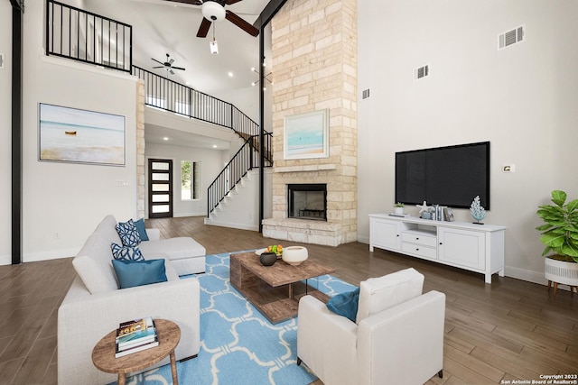 living area with stairs, a fireplace, visible vents, and wood finished floors