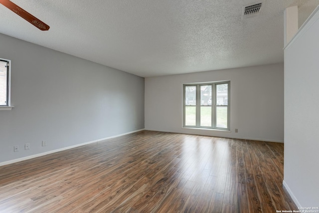 empty room with visible vents, a ceiling fan, a textured ceiling, wood finished floors, and baseboards