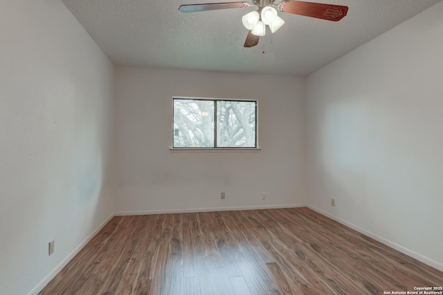 spare room featuring a textured ceiling, wood finished floors, a ceiling fan, and baseboards