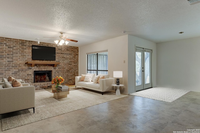 living room with a brick fireplace, ceiling fan, concrete floors, and a textured ceiling