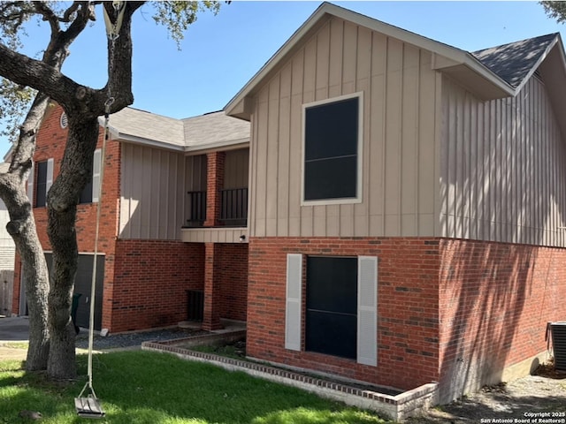 back of house with a garage, a yard, board and batten siding, and brick siding