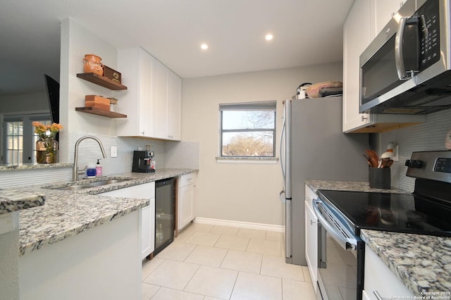 kitchen featuring open shelves, appliances with stainless steel finishes, a sink, and white cabinetry