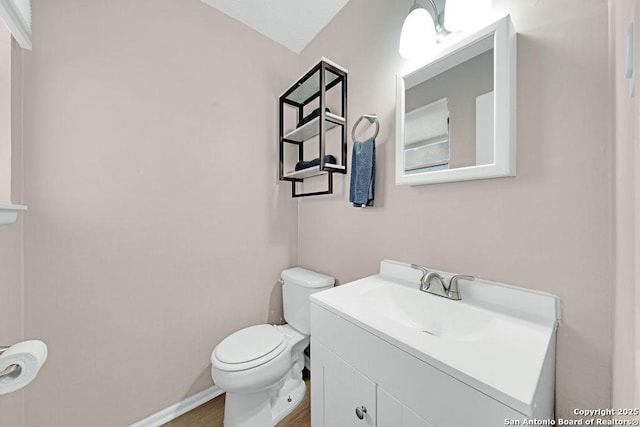 bathroom featuring baseboards, vanity, and toilet