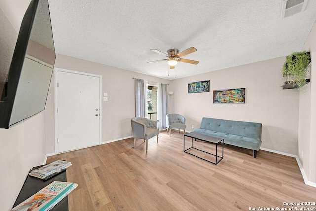 living area with visible vents, ceiling fan, a textured ceiling, and light wood-style flooring