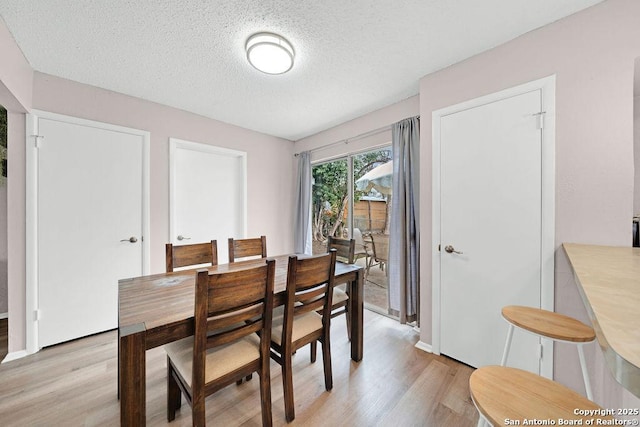 dining area featuring light wood finished floors and a textured ceiling