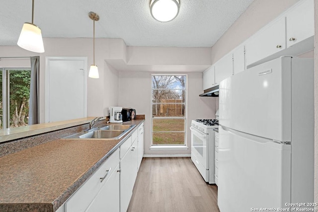 kitchen featuring a textured ceiling, white appliances, a sink, white cabinetry, and light wood-style floors