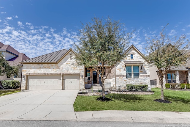 french provincial home featuring a garage, stone siding, metal roof, a standing seam roof, and a front lawn