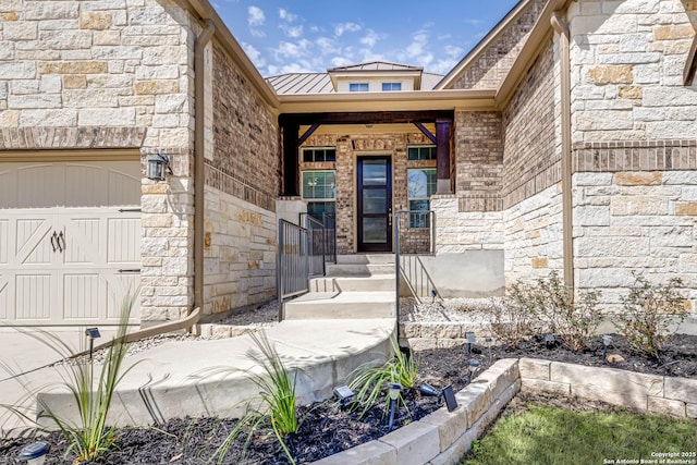 doorway to property with an attached garage, metal roof, a standing seam roof, and stone siding