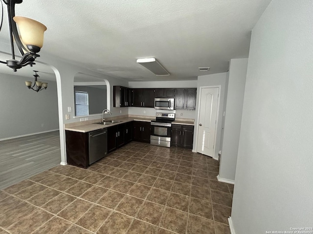 kitchen with arched walkways, light countertops, visible vents, appliances with stainless steel finishes, and a sink