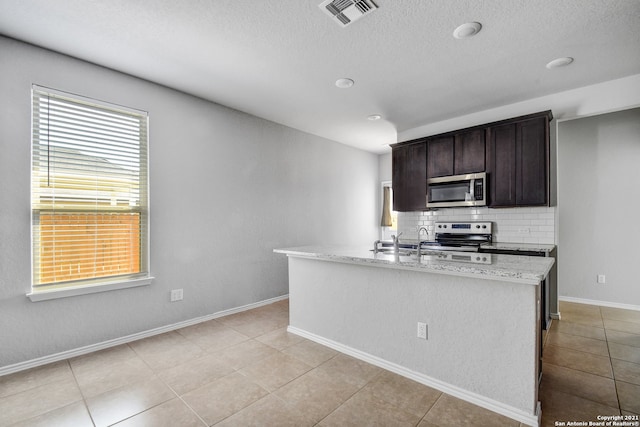 kitchen with dark brown cabinetry, visible vents, baseboards, appliances with stainless steel finishes, and tasteful backsplash