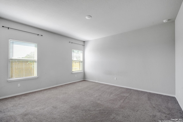 carpeted spare room featuring baseboards