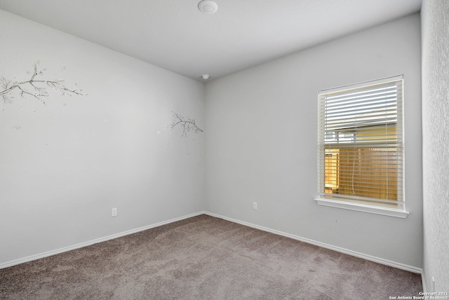 carpeted spare room featuring baseboards