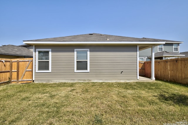 back of house featuring a yard and a fenced backyard