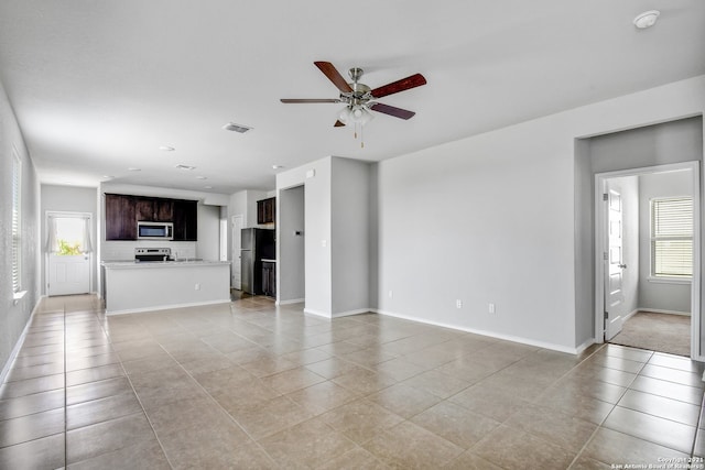 unfurnished living room featuring light tile patterned floors, ceiling fan, visible vents, and baseboards