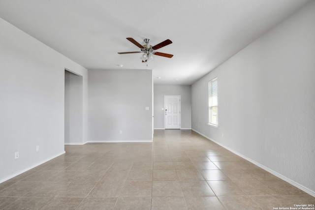 spare room featuring a ceiling fan, baseboards, and light tile patterned floors