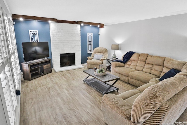 living room with a brick fireplace and wood finished floors