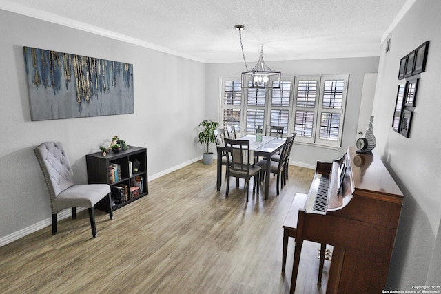 dining space featuring baseboards, a textured ceiling, an inviting chandelier, and wood finished floors