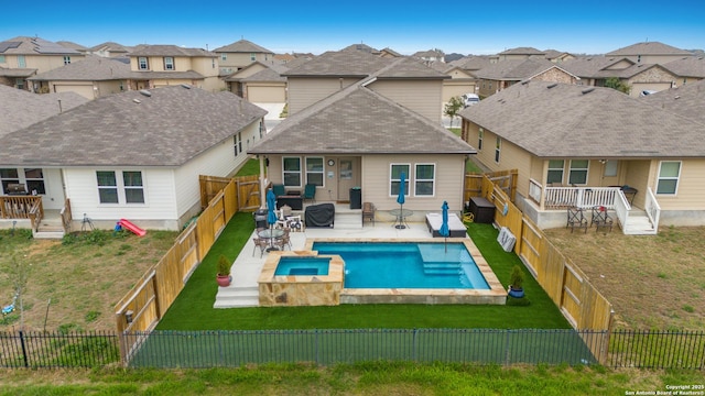 view of swimming pool featuring a patio, a pool with connected hot tub, a lawn, a residential view, and a fenced backyard