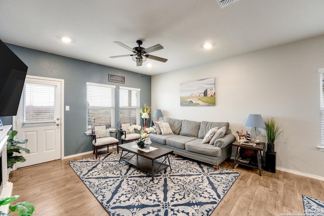 living room with light wood finished floors, ceiling fan, and baseboards