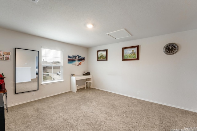 carpeted empty room featuring attic access and baseboards