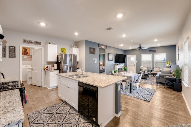 kitchen with visible vents, open floor plan, white cabinetry, a sink, and black appliances