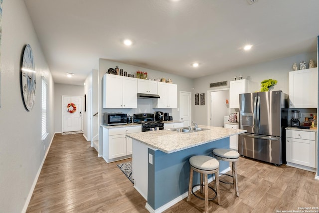 kitchen with stainless steel appliances, light wood-type flooring, a sink, and under cabinet range hood