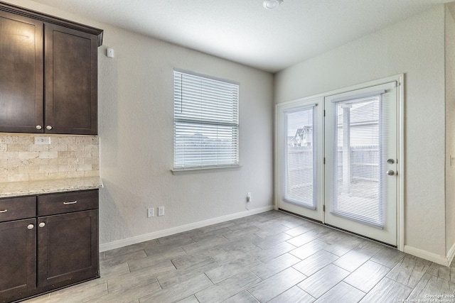 unfurnished dining area featuring light wood-type flooring and baseboards