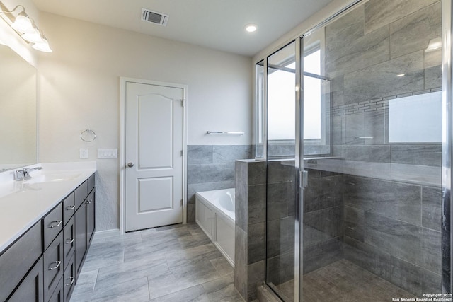 bathroom with double vanity, a garden tub, visible vents, and a stall shower