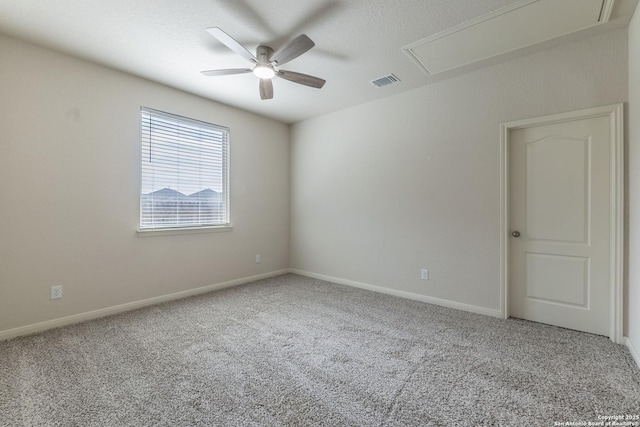 spare room with carpet flooring, visible vents, baseboards, a ceiling fan, and attic access