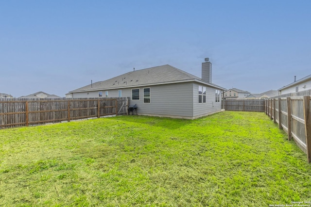 rear view of property with a fenced backyard, a lawn, and a chimney