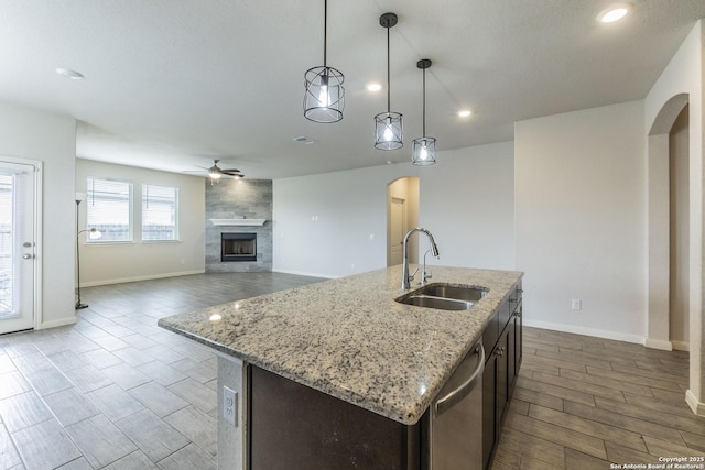 kitchen with dishwasher, arched walkways, a sink, and a ceiling fan