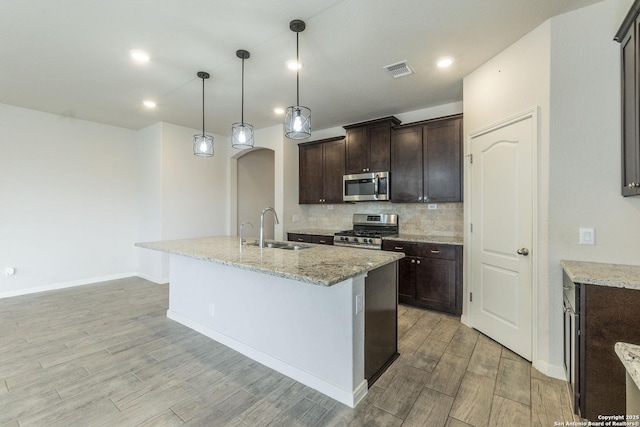 kitchen featuring tasteful backsplash, visible vents, arched walkways, appliances with stainless steel finishes, and a sink