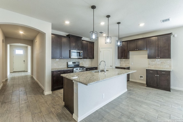 kitchen featuring light wood-style flooring, dark brown cabinetry, a sink, visible vents, and appliances with stainless steel finishes