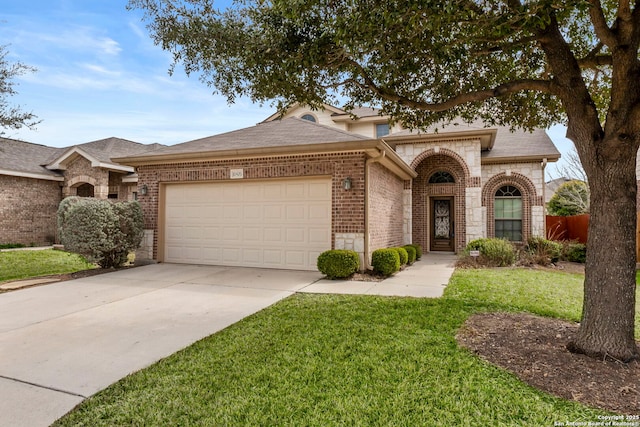 view of front of house with an attached garage, driveway, a front lawn, and brick siding