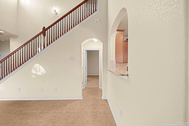 interior space featuring a high ceiling, baseboards, and arched walkways