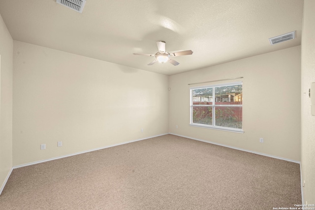 carpeted spare room with baseboards, visible vents, and a ceiling fan