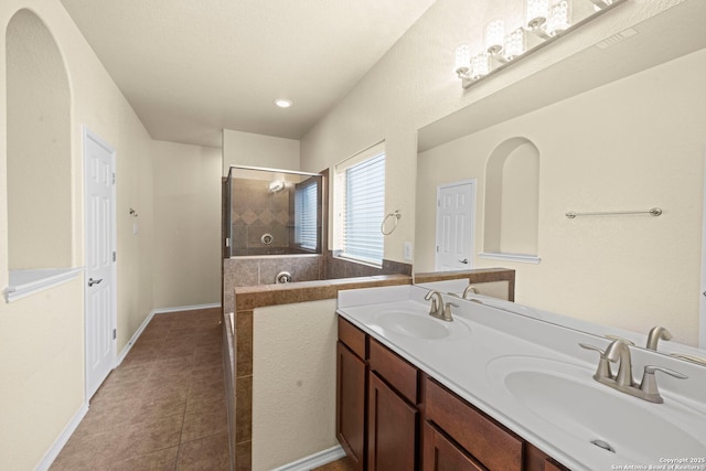 bathroom with a tile shower, double vanity, a sink, and tile patterned floors