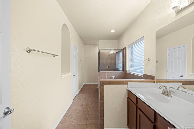 full bathroom featuring tile patterned flooring, baseboards, a tile shower, and vanity