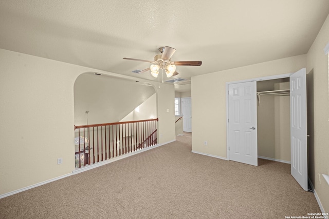 interior space featuring baseboards, a textured ceiling, visible vents, and a ceiling fan