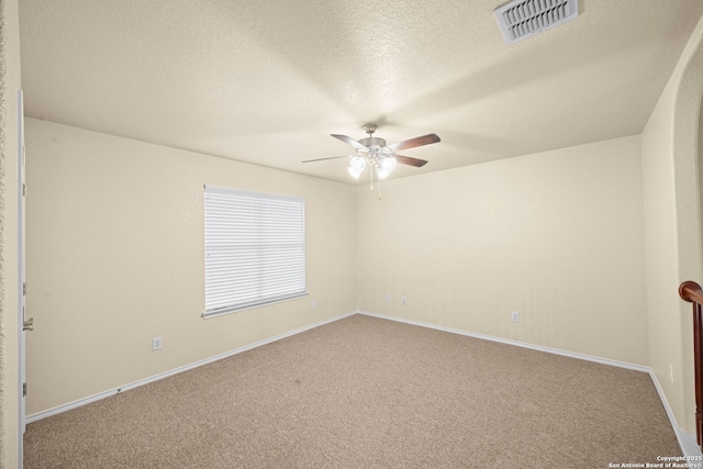 carpeted spare room featuring baseboards, ceiling fan, visible vents, and a textured ceiling