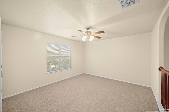 empty room featuring a textured ceiling, ceiling fan, carpet floors, visible vents, and baseboards