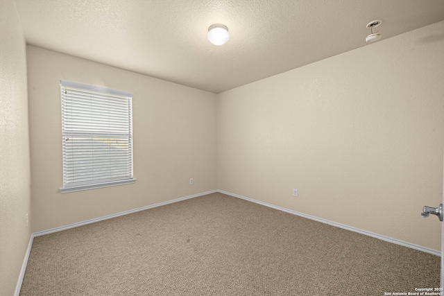 carpeted spare room featuring a textured ceiling and baseboards