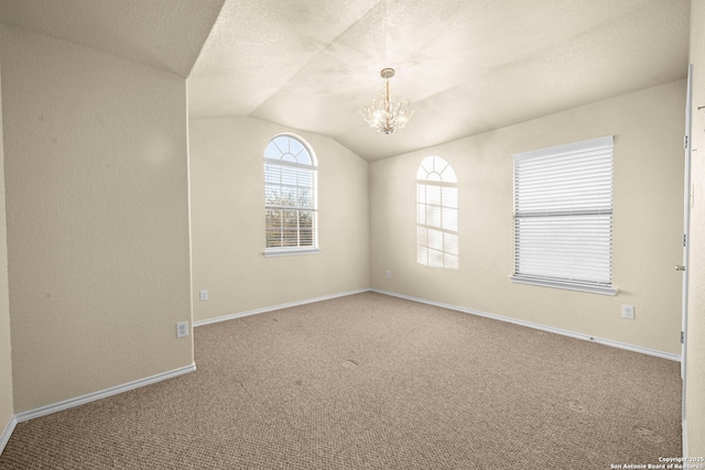 unfurnished room featuring lofted ceiling, a textured ceiling, a notable chandelier, carpet floors, and baseboards