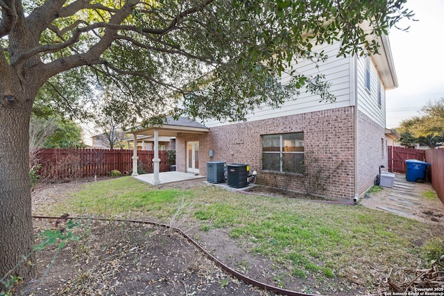 back of house with a fenced backyard, cooling unit, a yard, a patio area, and brick siding