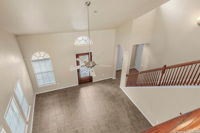 tiled foyer with a ceiling fan, a towering ceiling, and baseboards