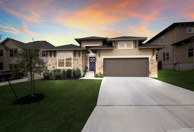 prairie-style house with stone siding, driveway, a front lawn, and stucco siding