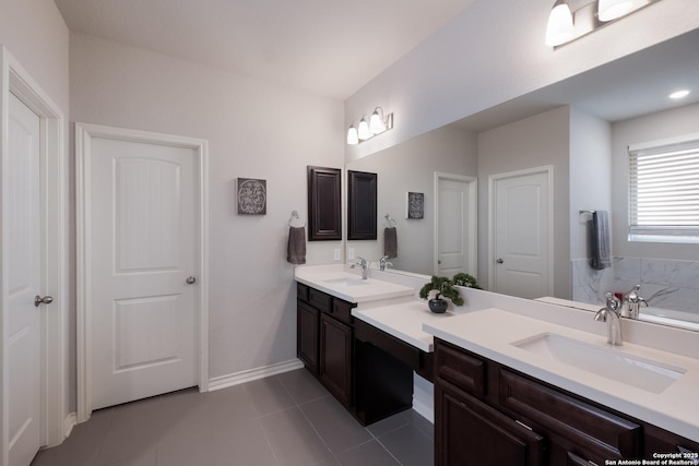 bathroom with tile patterned floors, a sink, baseboards, and double vanity