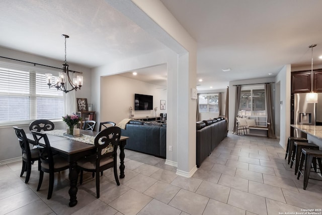 dining space with light tile patterned floors, baseboards, and a notable chandelier